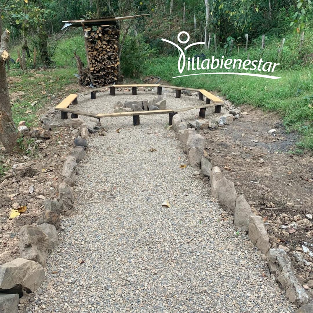 Círculo de fuego de Villa Bienestar con sendero de piedra y bancas